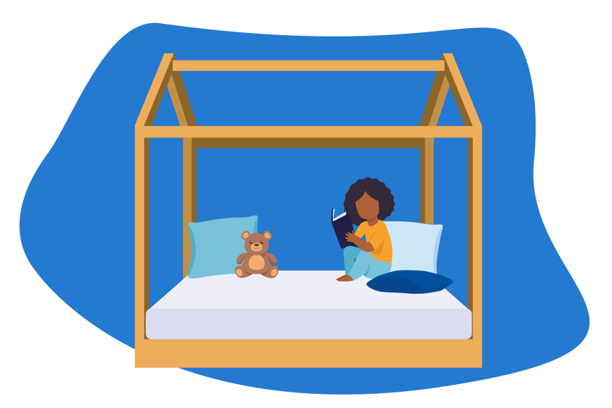 Cama de criança Montessori a ser utilizada por uma criança a ler um livro, com duas almofadas e um ursinho de peluche